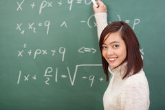 smiling-young-student-teacher-doing-maths-female-asian-standing-blackboard-covered-mathematical-equations-39549936